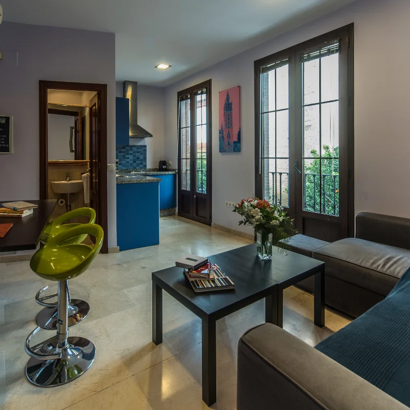 Sala moderna con cocina azul y taburetes verdes.