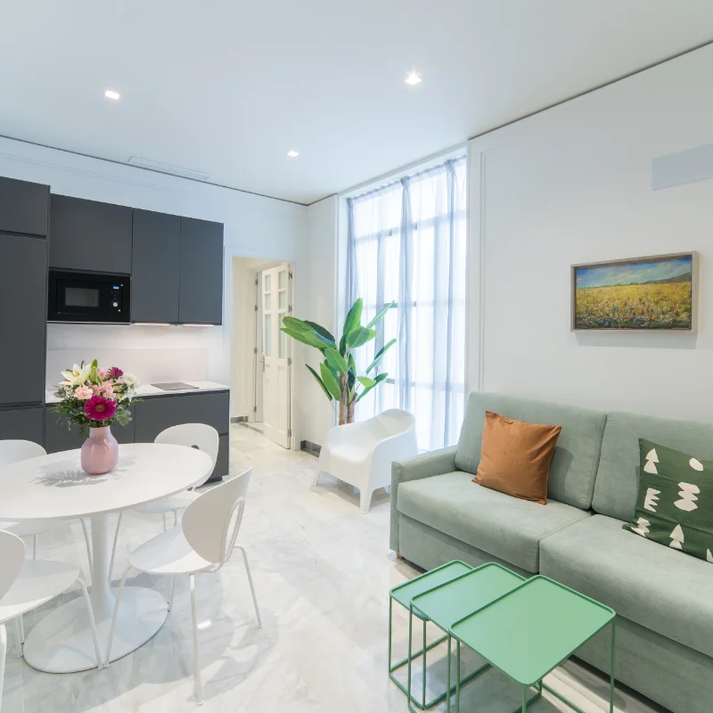 Sala moderna con sof&aacute; verde y mesa redonda blanca.