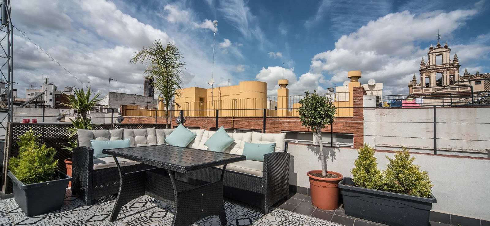 Terraza amueblada con vista a la ciudad, cielo parcialmente nublado.
