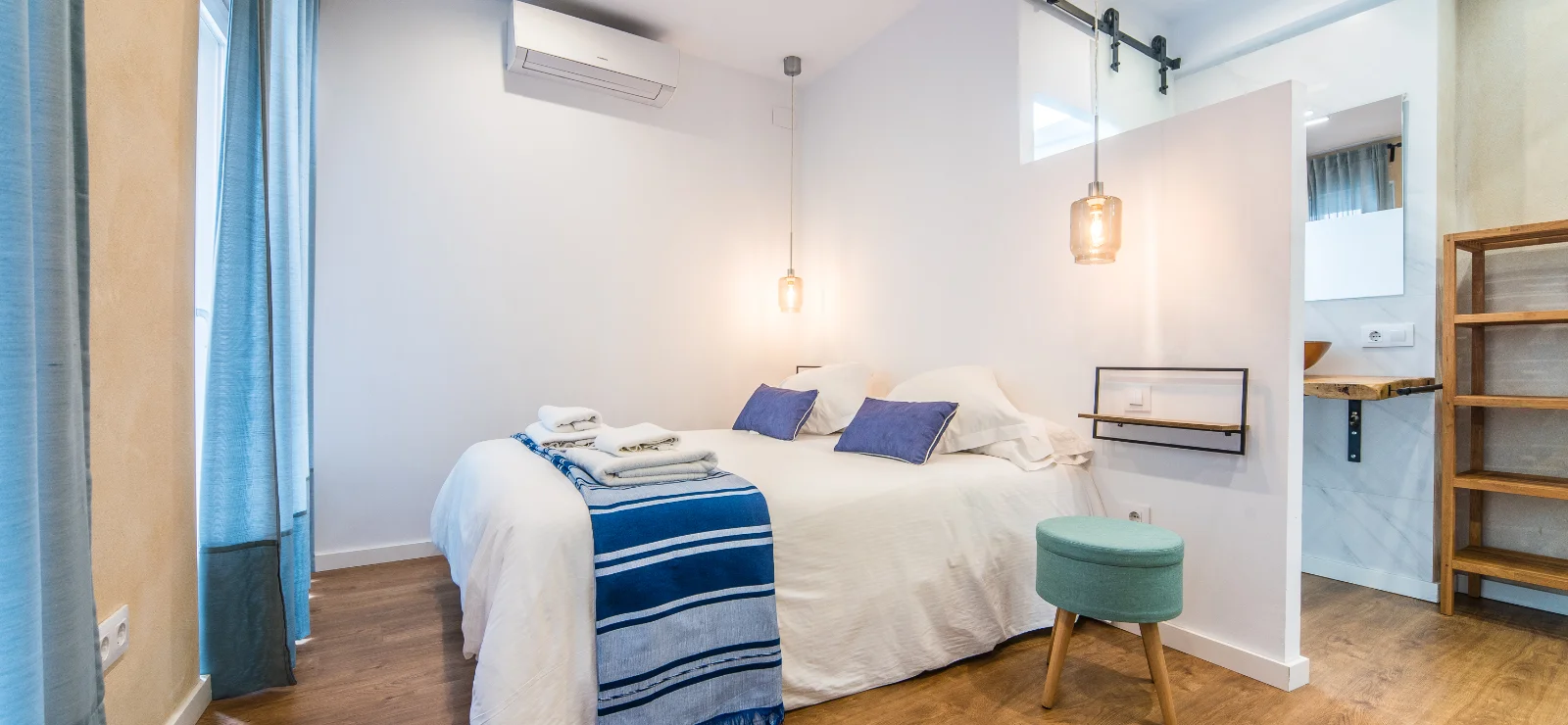 Dormitorio minimalista con cama, decorado en tonos azules y madera clara.