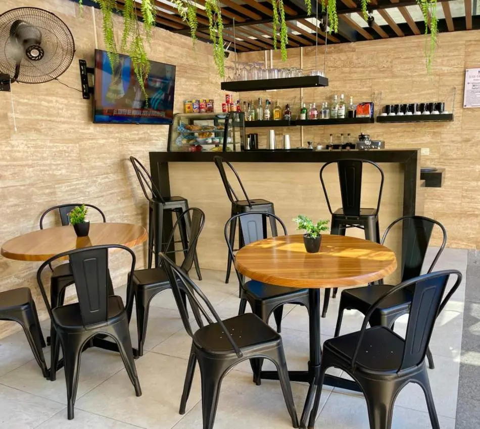 Terraza moderna con mesa, sillas negras y pared de madera.