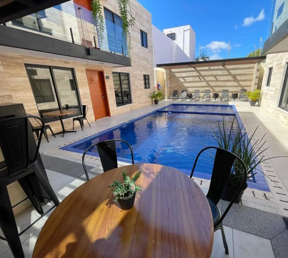 Patio moderno con piscina, mesas y sillas negras.