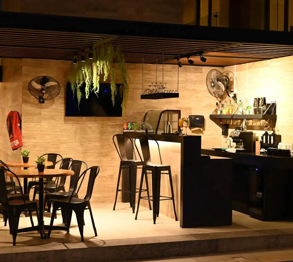 Vista de noche de terraza moderna con mesa, sillas negras y pared de madera.