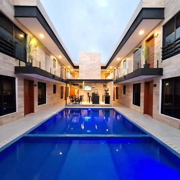 Patio con piscina azul rodeado de paredes de piedra beige y balcones con plantas.