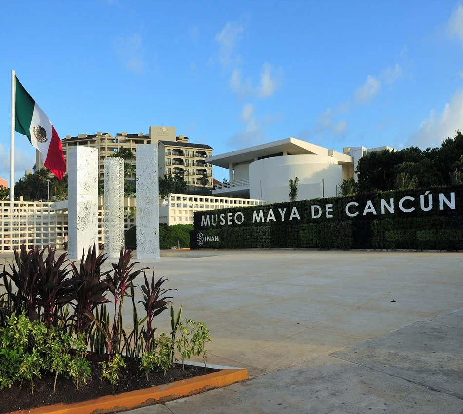 Entrada del Museo Maya de Canc&uacute;n con bandera mexicana ondeando.