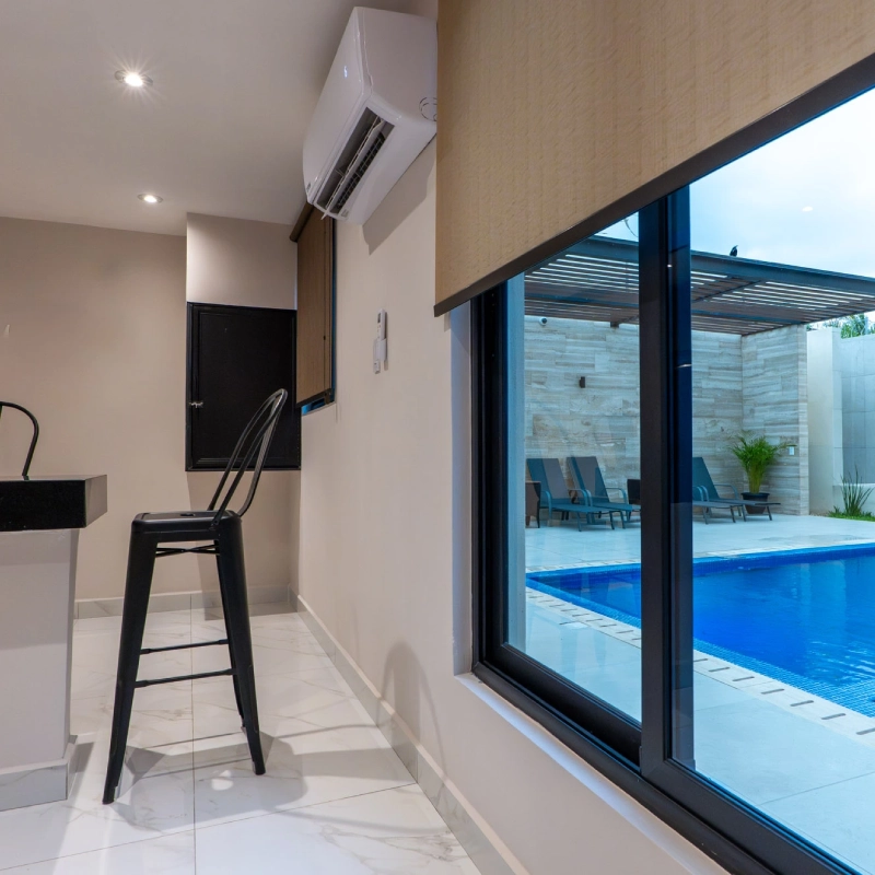 Interior minimalista con vista a piscina a trav&eacute;s de ventana.