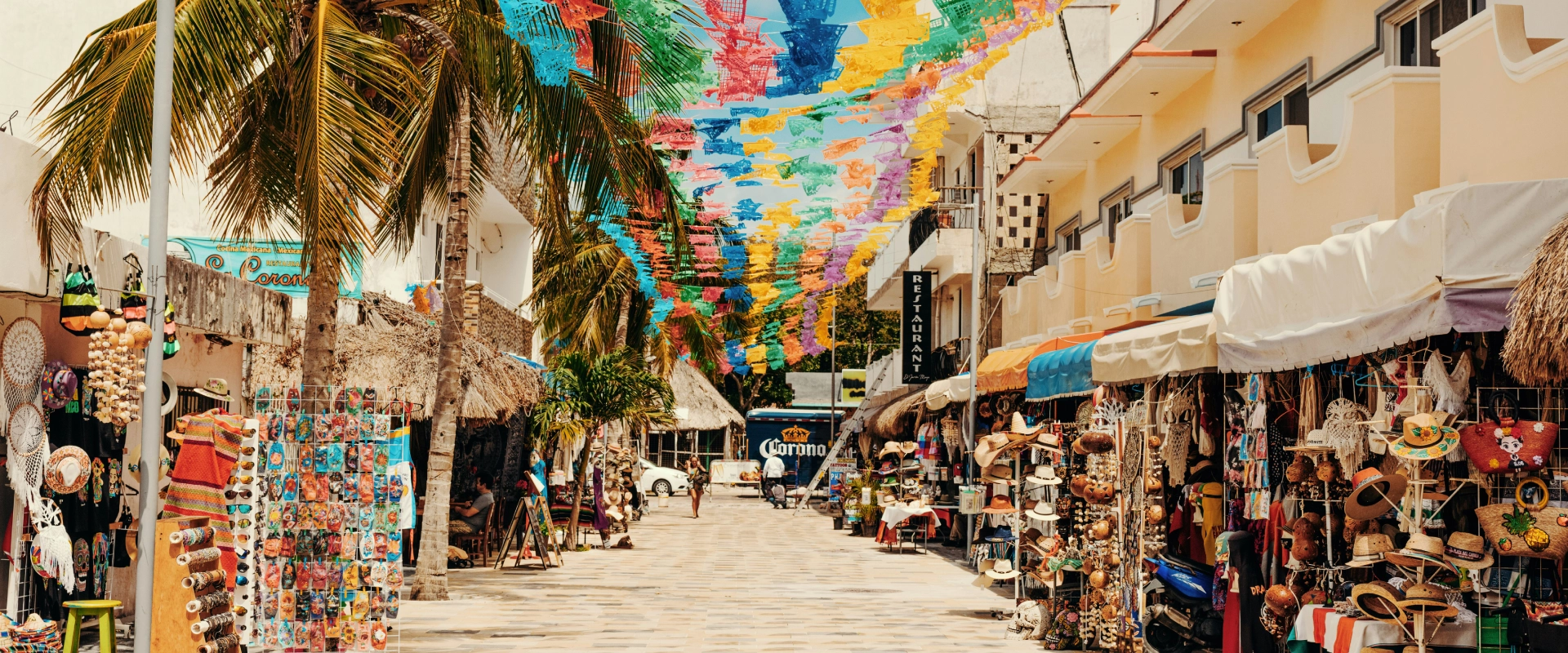 Mercado callejero con artesan&iacute;as, banderines y palmeras.