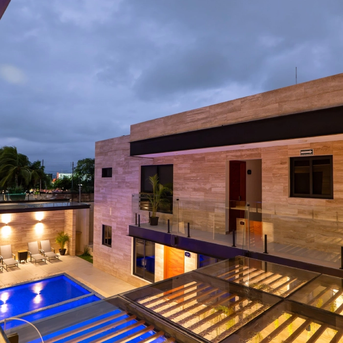 Moderna casa con piscina iluminada al anochecer.