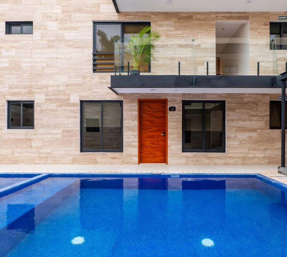 Fachada moderna con piscina frontal y balc&oacute;n decorado con planta.