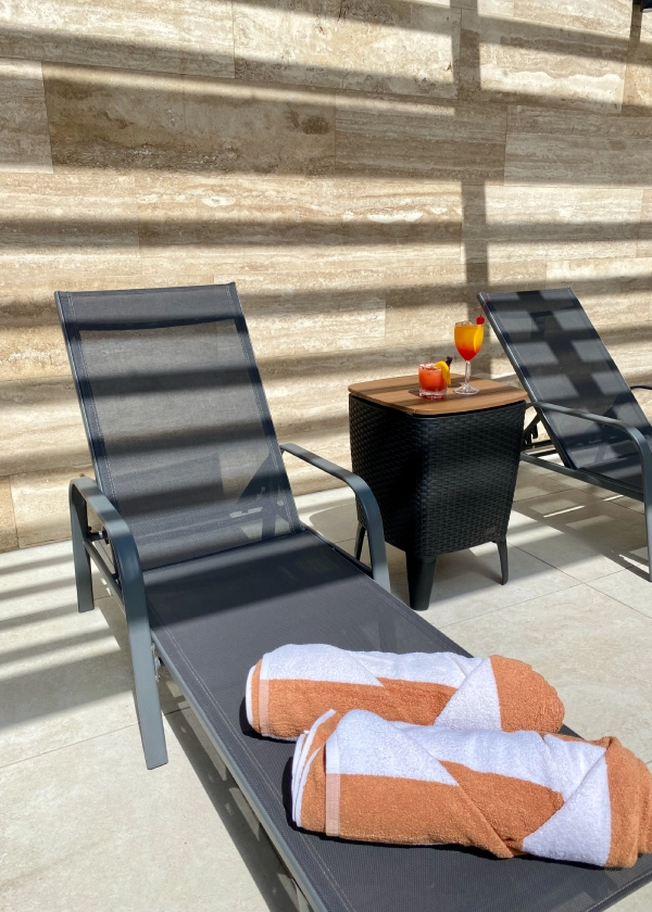 Tumbonas con toallas y bebidas en un patio soleado.