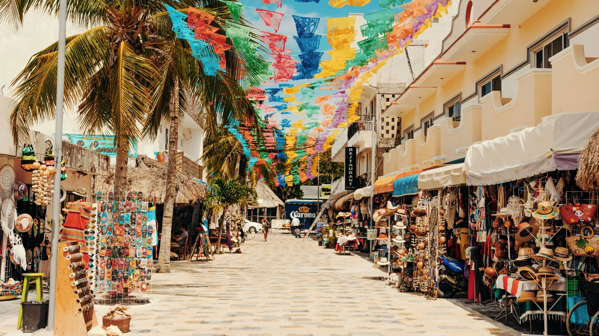 Calle colorida con tiendas y banderines en un mercado al aire libre.