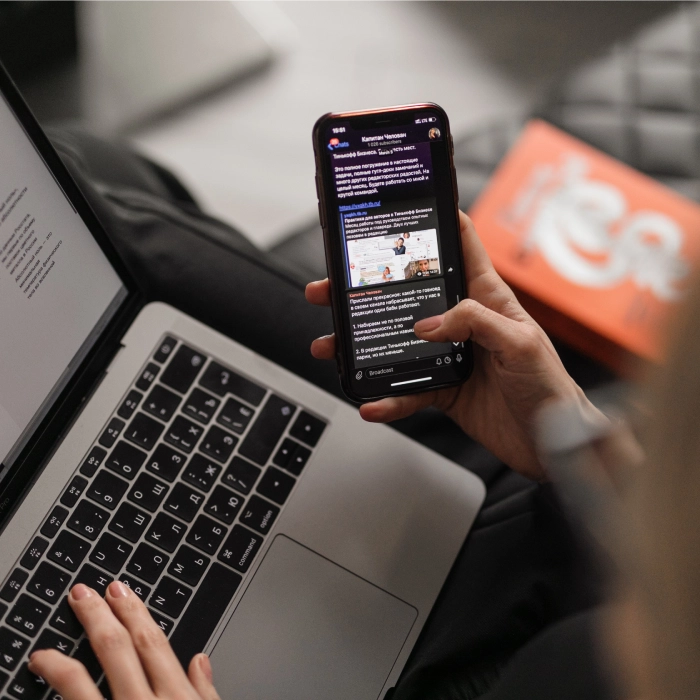 Persona usando un smartphone y una laptop simult&aacute;neamente.