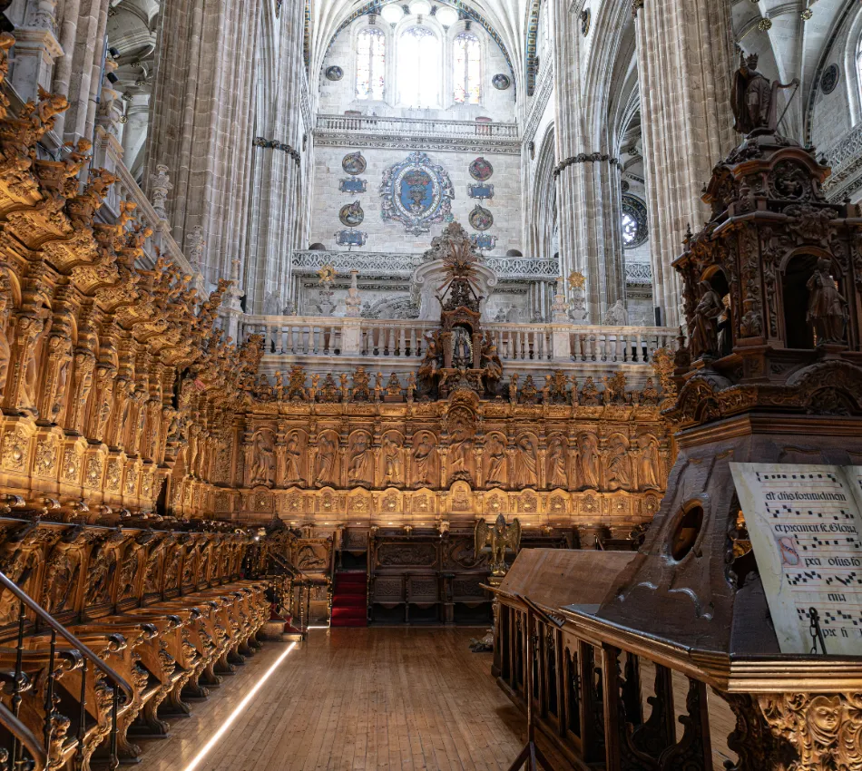 Interior de una catedral con elaborados asientos de madera tallada y arquitectura g&oacute;tica.