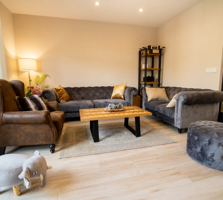 Sala de estar moderna con sillones grises, mesa de madera y l&aacute;mpara de pie iluminando el espacio.