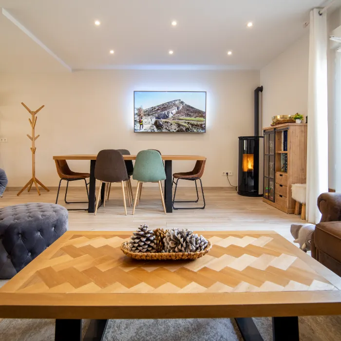 Sala moderna con mesa, sillas de colores, estufa, y televisor, pi&ntilde;as decorativas sobre la mesa.