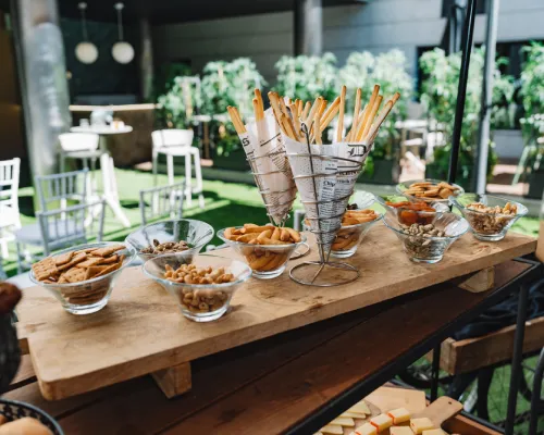 Mesa de aperitivos con snacks y pan en un ambiente al aire libre.