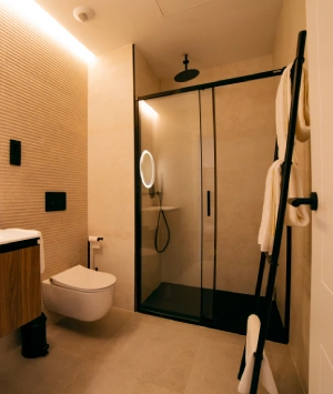 Ba&ntilde;o moderno con ducha acristalada y toallas en un soporte de escalera.