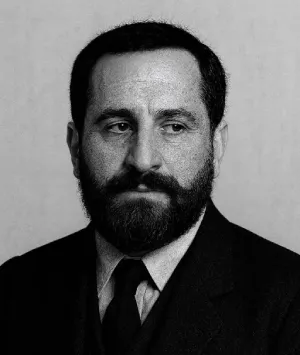 Hombre de barba con traje oscuro en blanco y negro, mirando a su derecha.