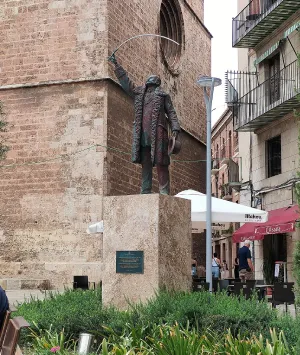 Estatua de un hombre con espada en una plaza medieval.