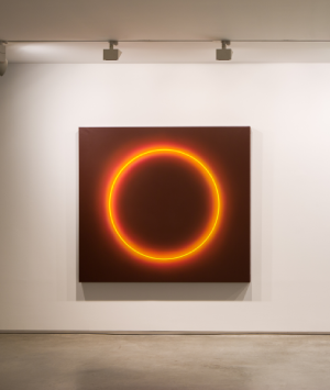 Cuadro cuadrado con c&iacute;rculo luminoso naranja en pared blanca de galer&iacute;a.