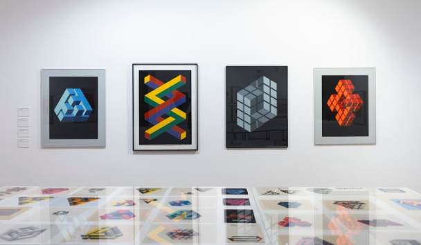 Cuatro cuadros geom&eacute;tricos coloridos colgados en una galer&iacute;a de arte.