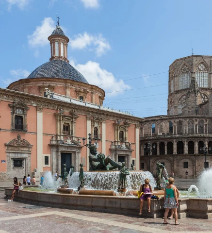 Fuente en una plaza con edificios hist&oacute;ricos y personas alrededor.