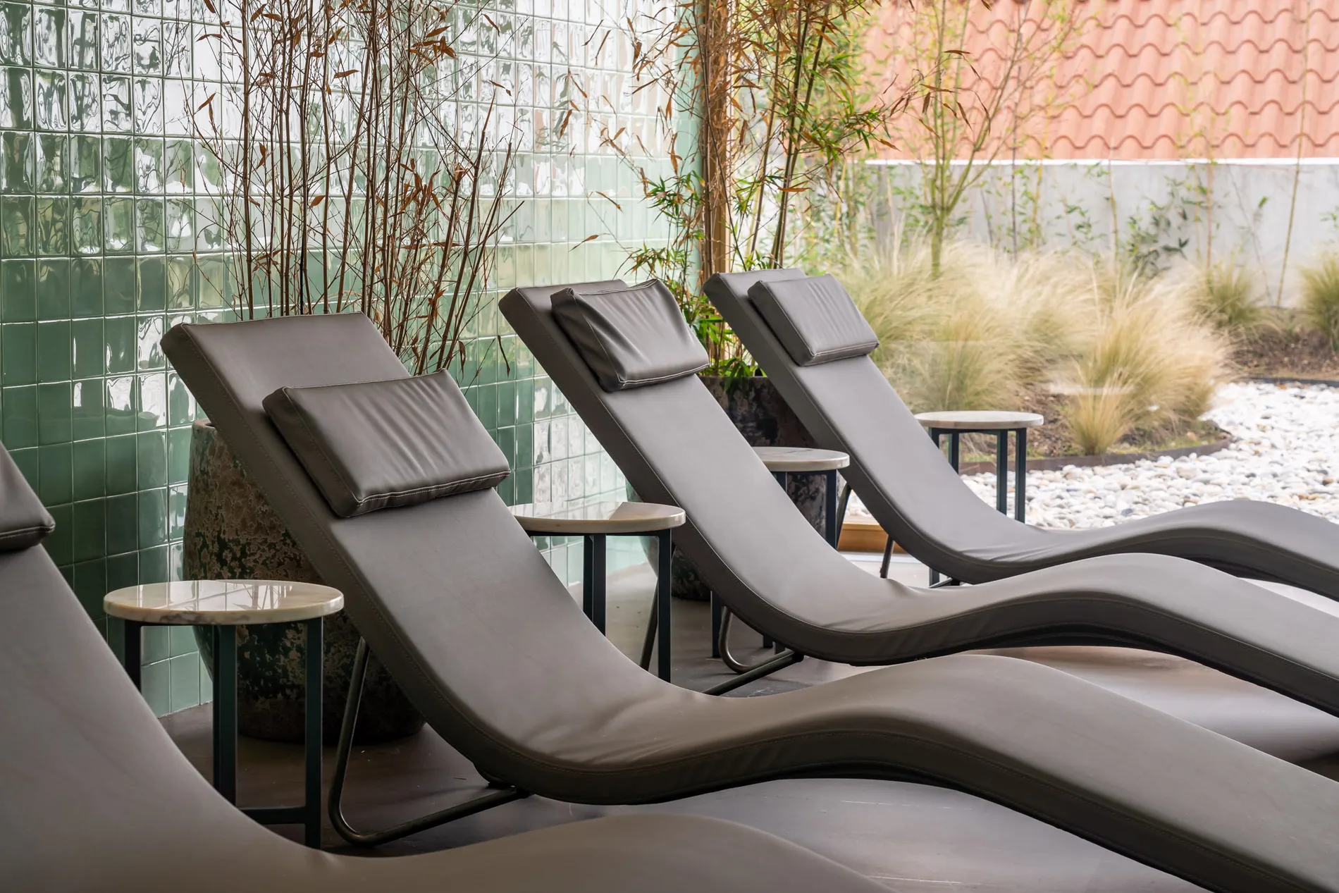 Espregui&ccedil;adeiras cinzas em um ambiente externo com parede verde e plantas ao fundo.