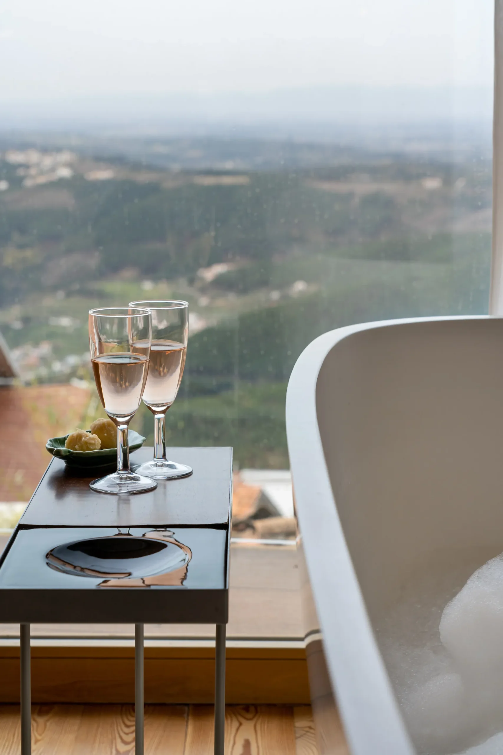 Ta&ccedil;a de espumante e banheira com vista panor&acirc;mica para a paisagem campestre.