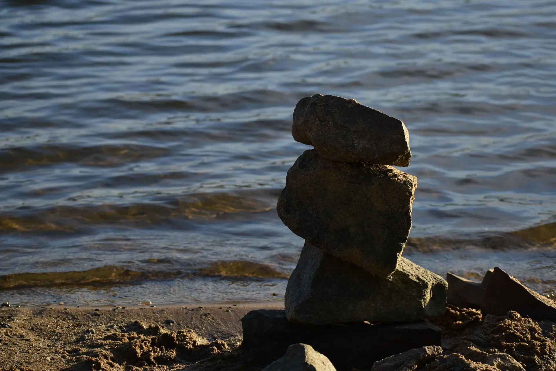 Pedras empilhadas na beira de um lago em um dia ensolarado.