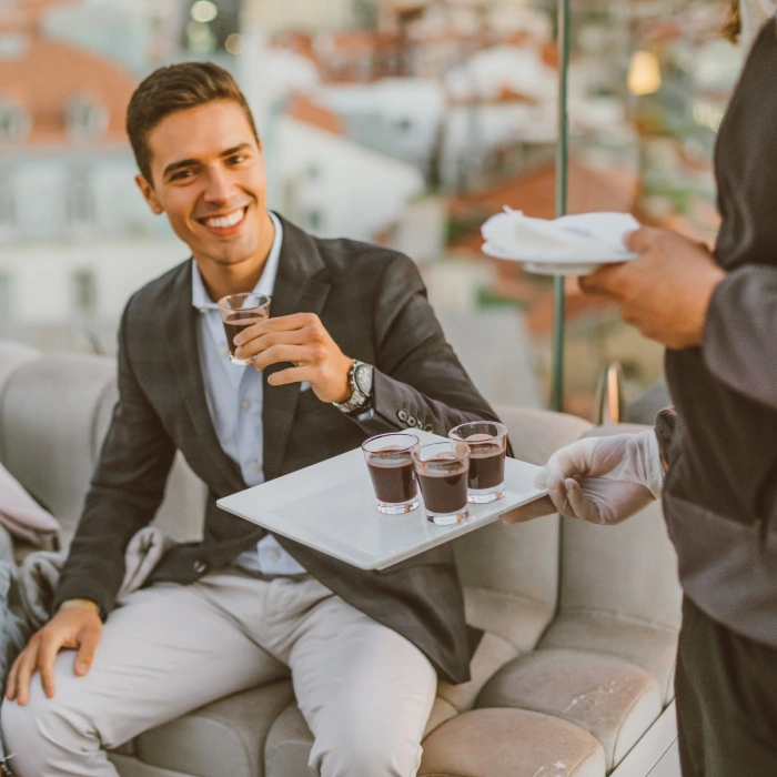 Homem sorrindo recebendo bebidas em um terra&ccedil;o.