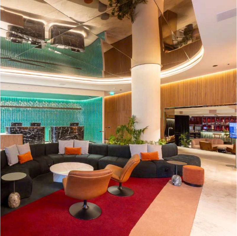Sagu&atilde;o de hotel modernamente decorado com sof&aacute;s e poltronas coloridas.