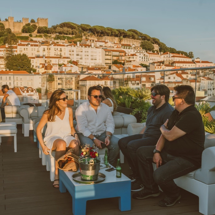 Pessoas conversam em um terra&ccedil;o com vista para cidade hist&oacute;rica.