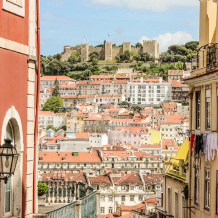 Vista do Castelo de S&atilde;o Jorge em Lisboa com casas coloridas em primeiro plano.