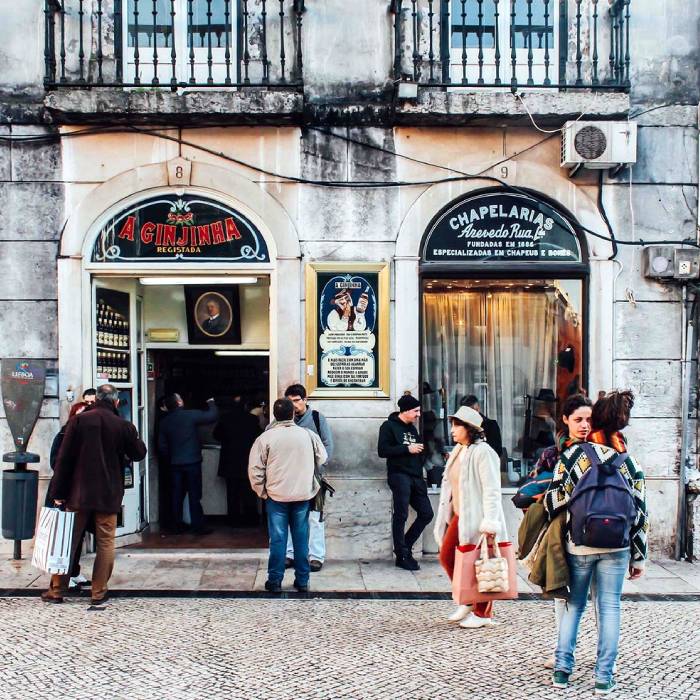 Pessoas em frente a uma loja hist&oacute;rica em uma rua movimentada.