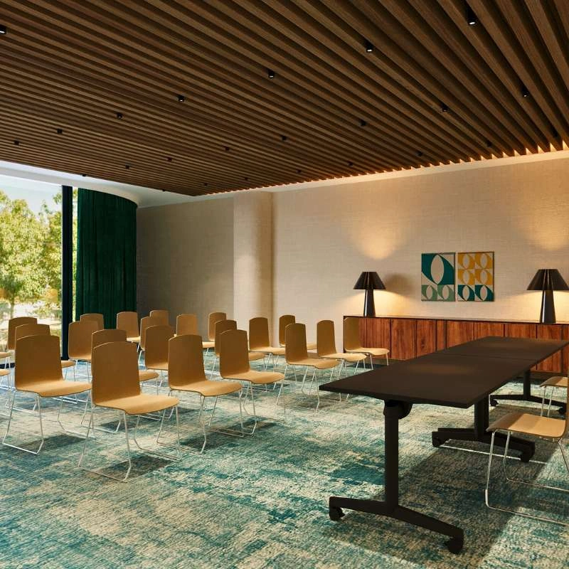 Sala de confer&ecirc;ncias moderna com cadeiras e mesa preta em destaque.