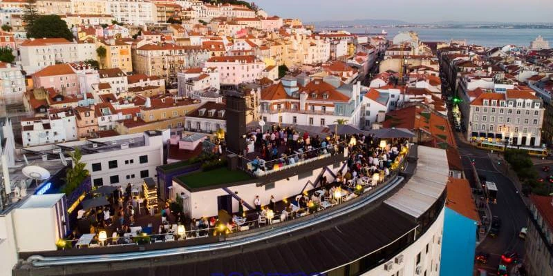 Vista a&eacute;rea de um terra&ccedil;o lotado em uma cidade com pr&eacute;dios hist&oacute;ricos ao fundo.