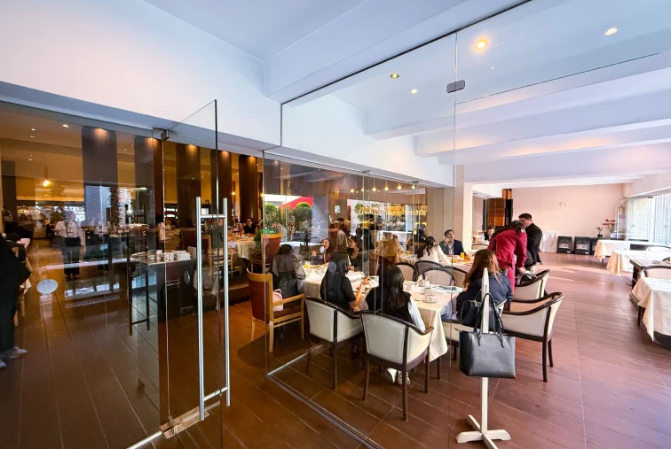 Personas cenando en un elegante restaurante con paredes de cristal.