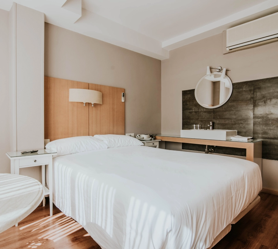 Habitaci&oacute;n de hotel moderna con cama, lavabo y luz natural.
