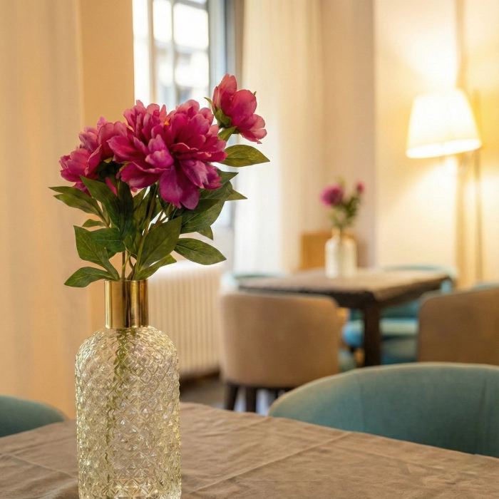 Florero con flores rosas en una mesa en un interior acogedor y iluminado.