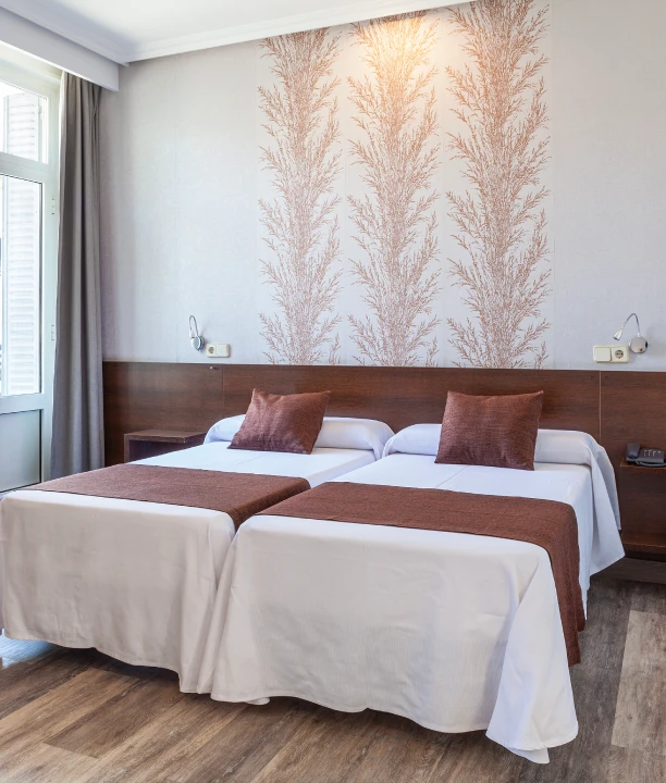 Habitaci&oacute;n de hotel con dos camas individuales y decoraci&oacute;n elegante.