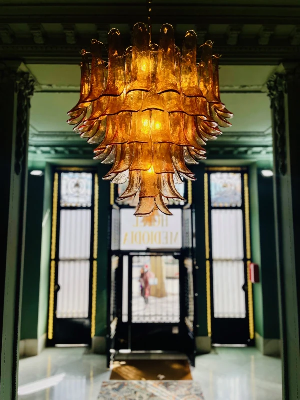 L&aacute;mpara de cristal &aacute;mbar colgante en un elegante vest&iacute;bulo iluminado.