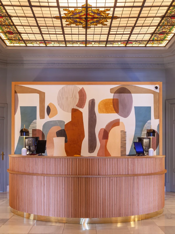 Mostrador con mural abstracto y techo de vidrieras decorativas.