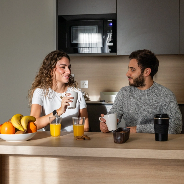 Dos personas tomando caf&eacute; y jugo en una cocina.