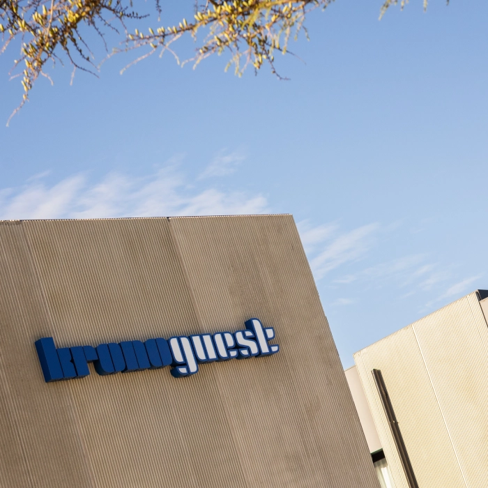 Edificio con el logo "kronoguest" en fachada bajo un cielo azul.