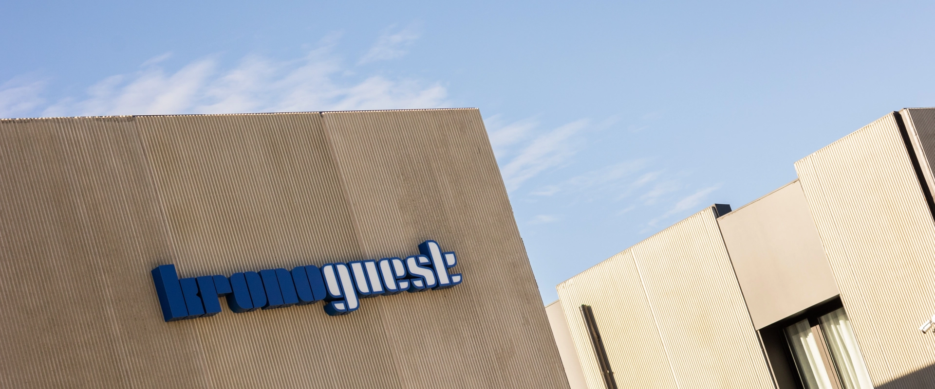Edificio moderno con logo azul en la fachada y cielo despejado.