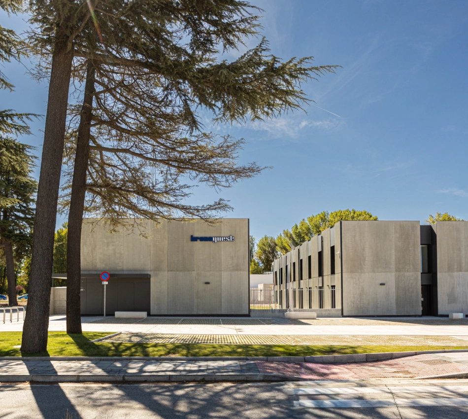 Edificio moderno de concreto con &aacute;rboles al frente en un d&iacute;a soleado.