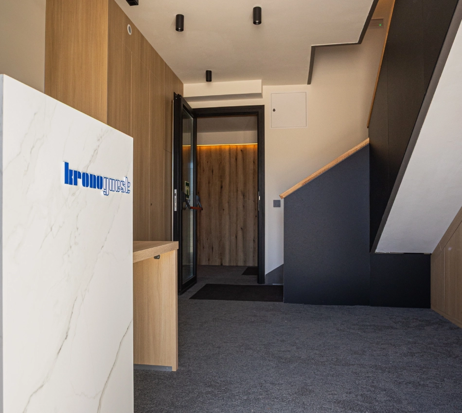 Entrada moderna con escalera, mostrador y puerta de cristal al fondo.