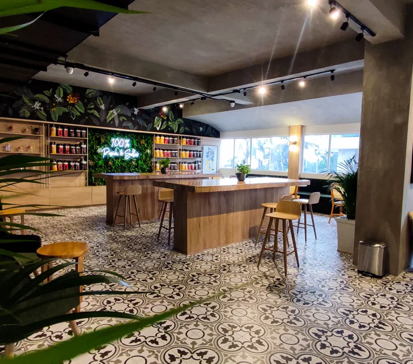 Cafeter&iacute;a moderna con barra central y decoraci&oacute;n vegetal.