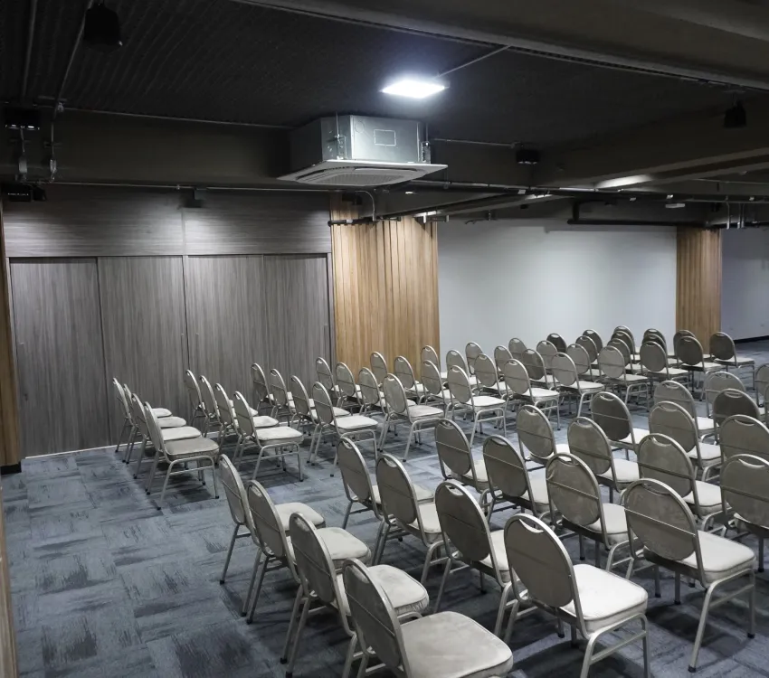 Sala de conferencias vac&iacute;a con sillas ordenadas en filas.