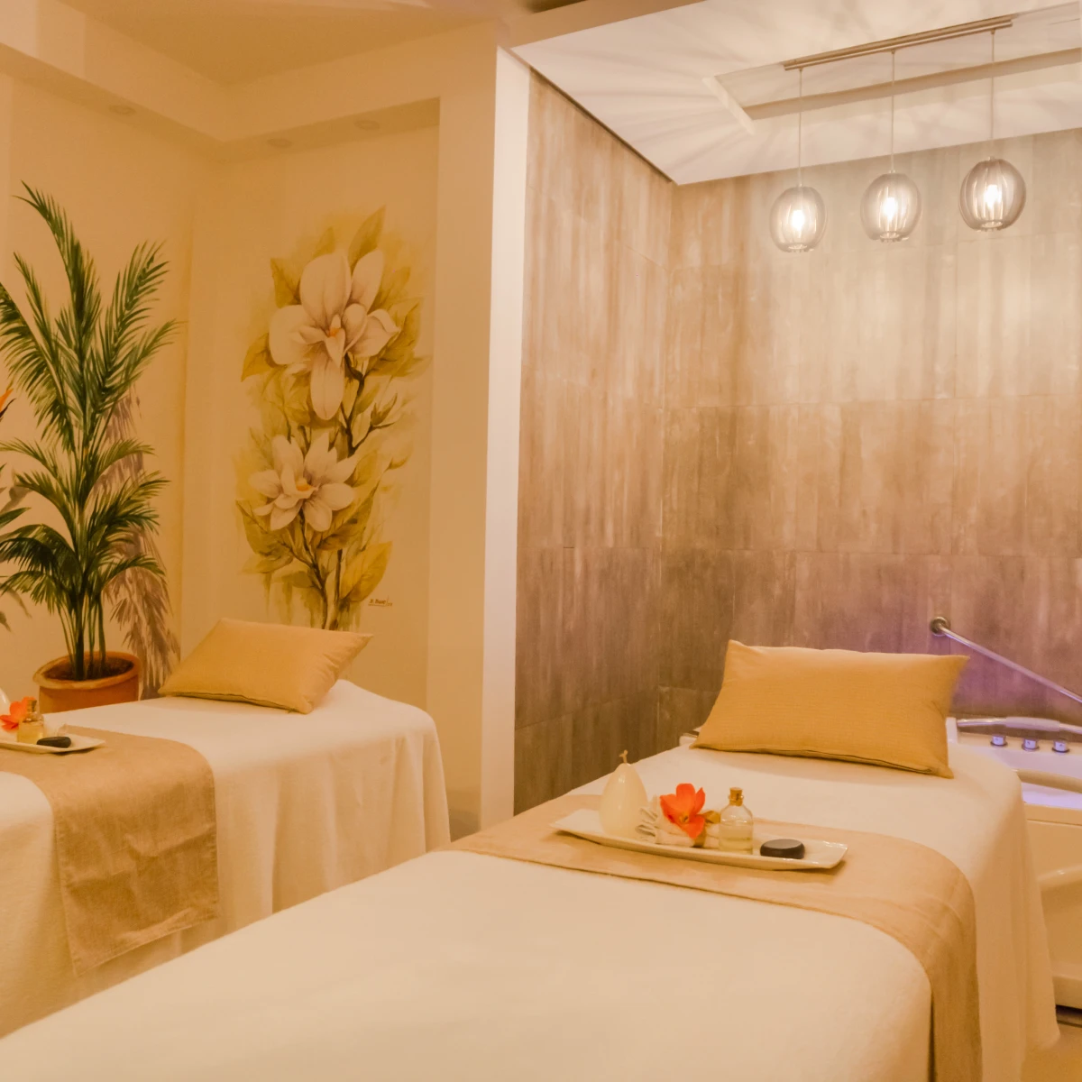 Spa con dos camillas, planta y decoración de flores en pared.